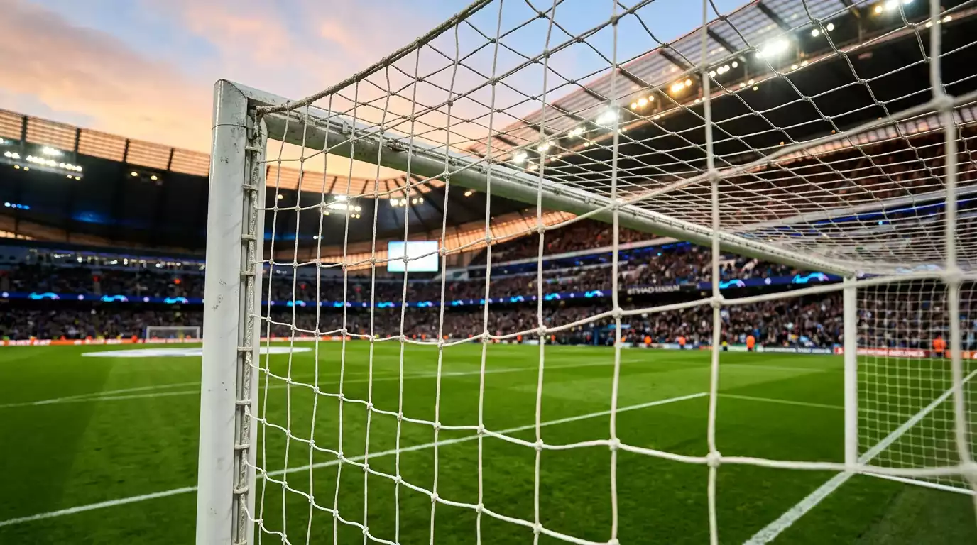 Futbola laukums ar tribīnēm un vārtu tīklu vakara apgaismojumā